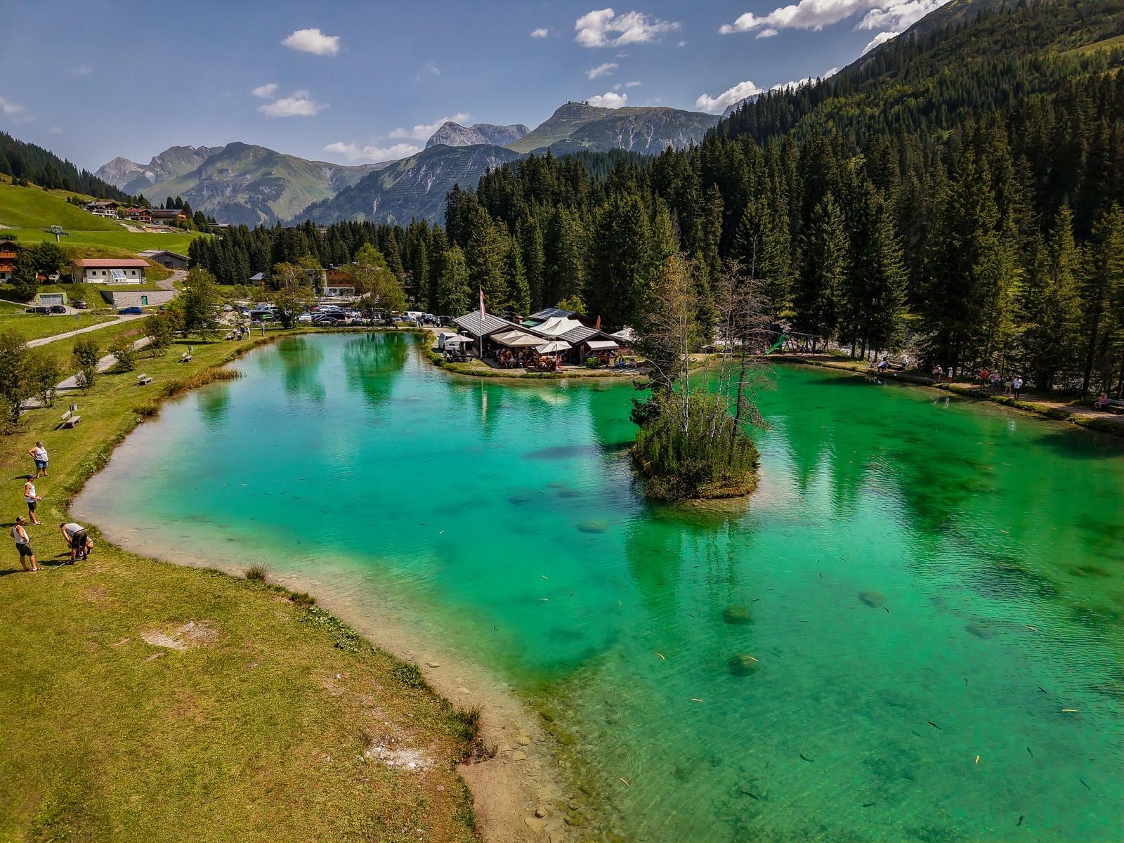Luftbild des Fischteichs in Zug mit dem Restaurant Fischerwirt und den umliegenden Bergen